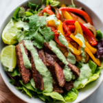 Vibrant Steak Fajita Salad with Avocado Dressing Vibrant steak fajita salad topped with creamy avocado dressing, made with fresh vegetables and marinated flank steak, perfect for festive occasions.